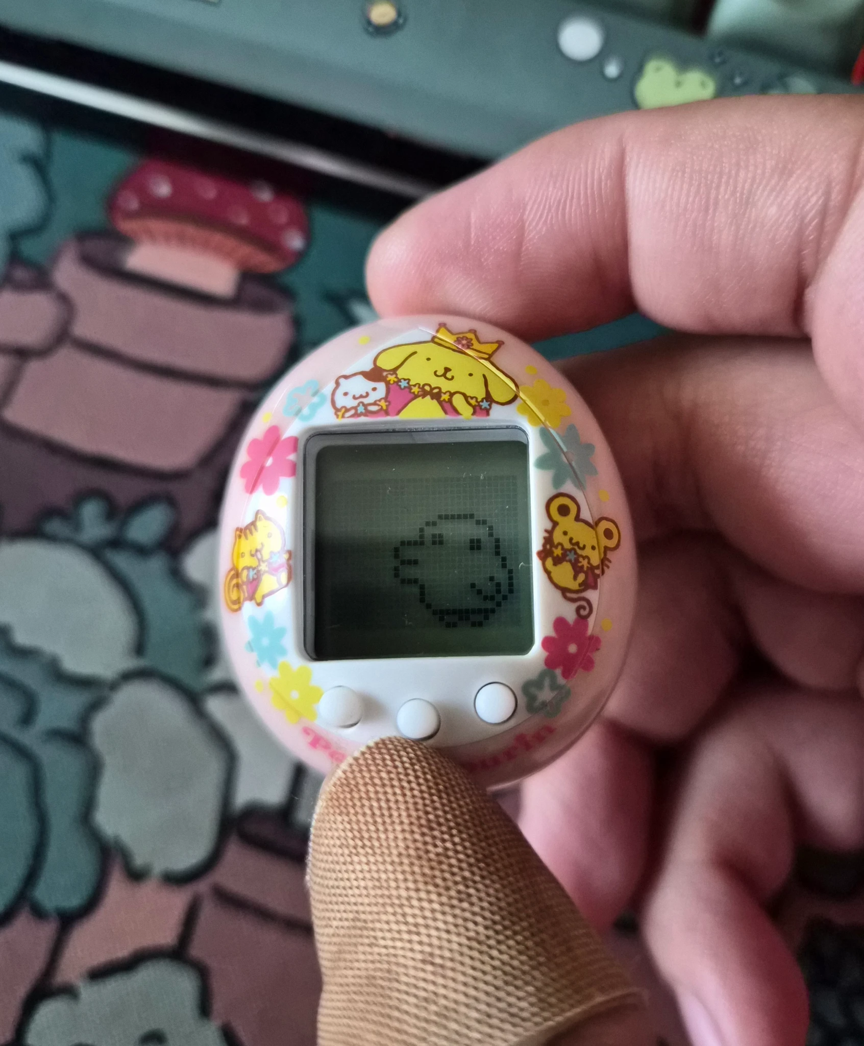 A tamagotchi mini themed after the Pompompurin character from Sanrio. My tamagotchi is a cute bird/duck type thing with derpy eyes and mouth.