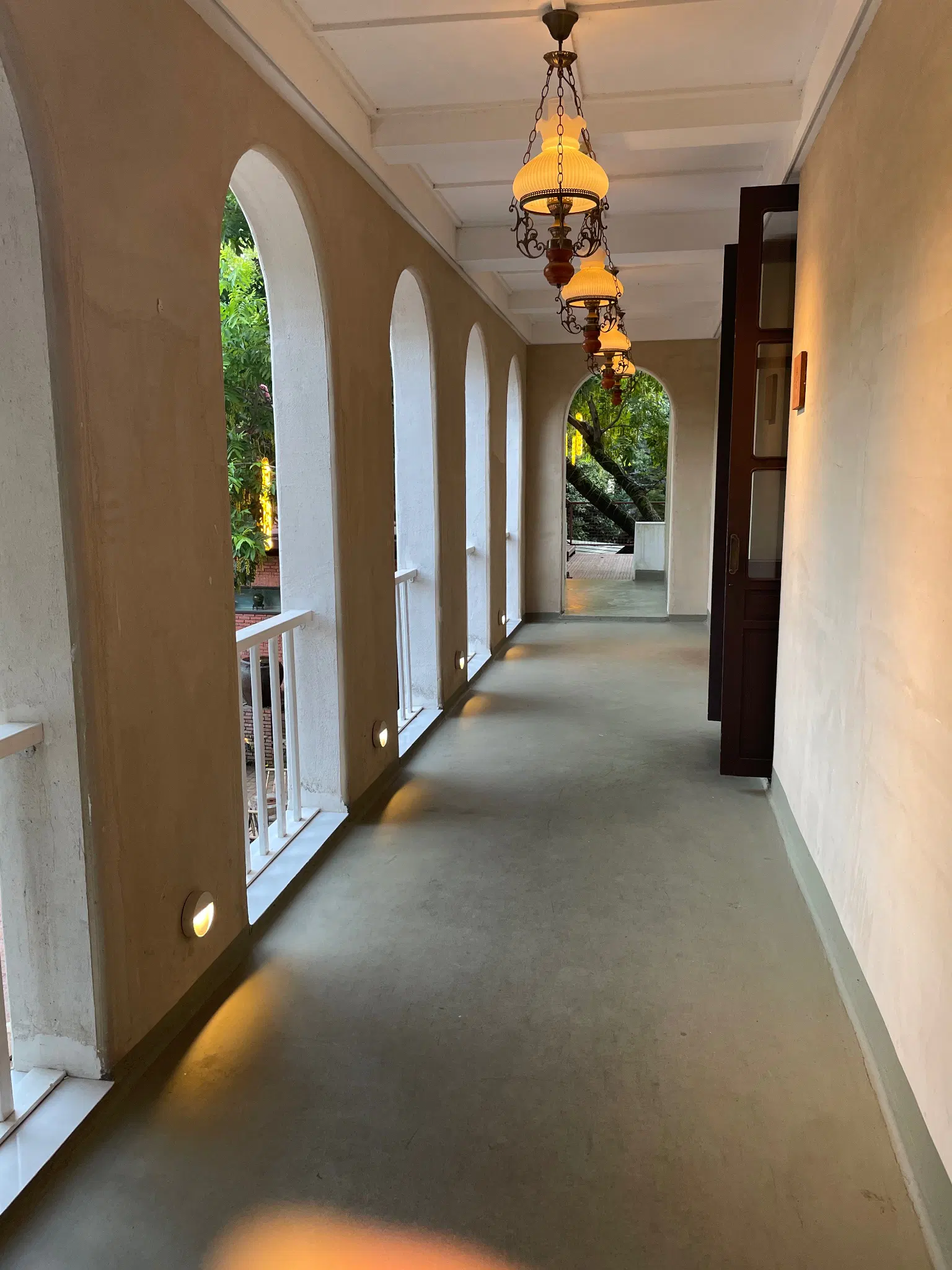 white hallway with arches to the left and wooden doors to the right

golden chandeliers at the top for lighting